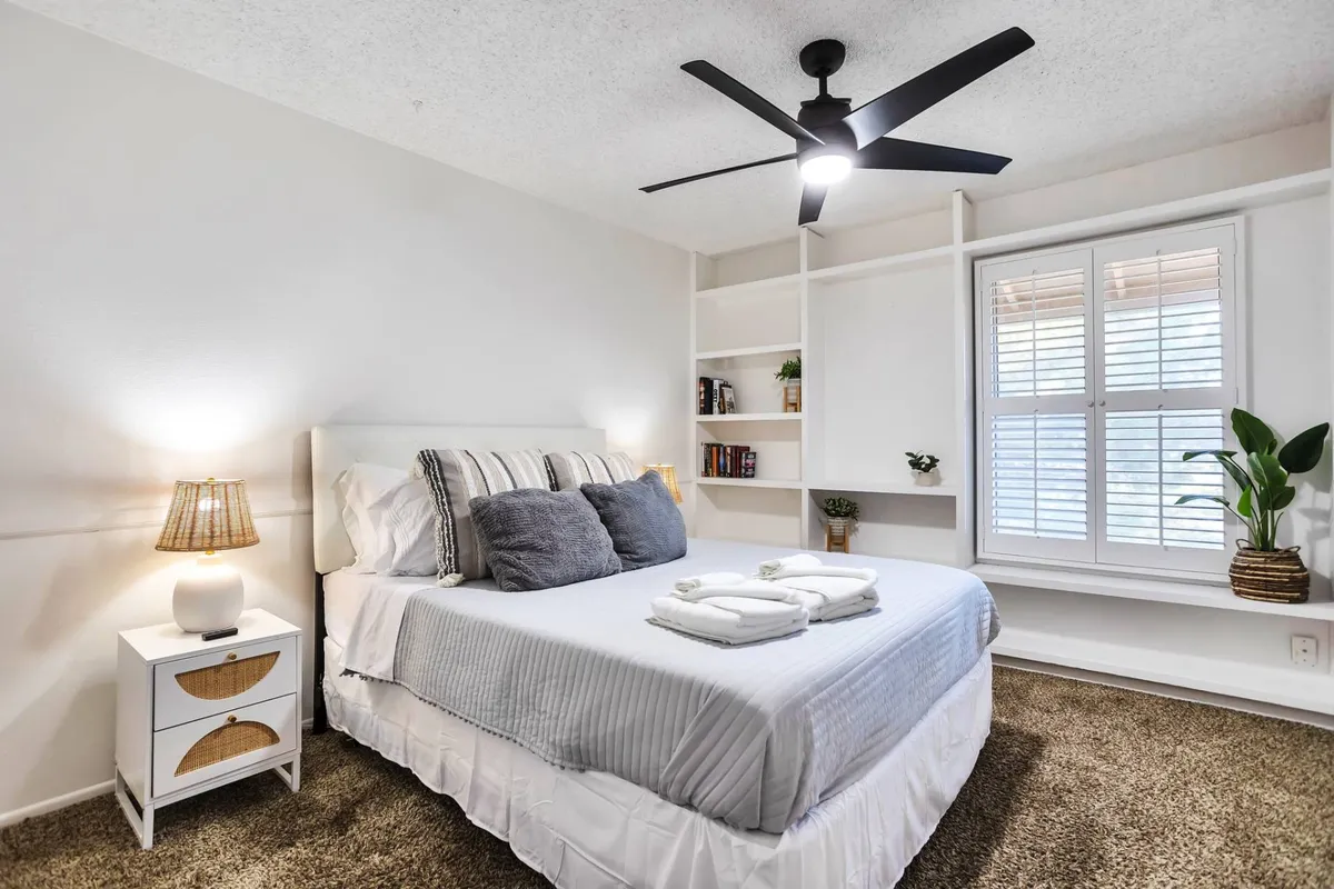 A serene bedroom scene with a bed, bookshelf, window, and soft lighting, creating a peaceful retreat for rest and privacy. The space feels cozy and quiet, suitable for recharging after a busy day.