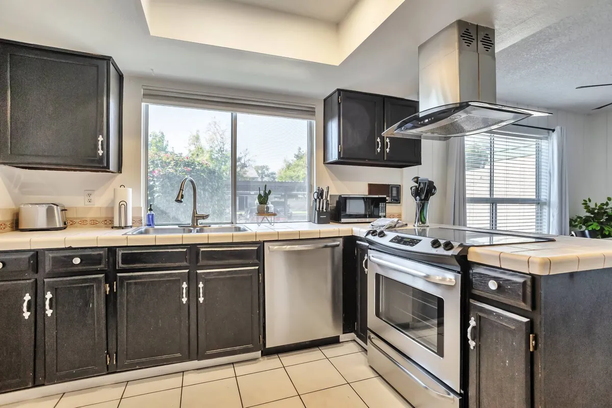 Here, the focus is on the kitchen countertop, modern stainless steel appliances, and a large window, creating a fresh and welcoming ambiance. This scene suggests both culinary creativity and the practical comforts of a fully equipped kitchen, ideal for preparing family feasts or casual snacks.